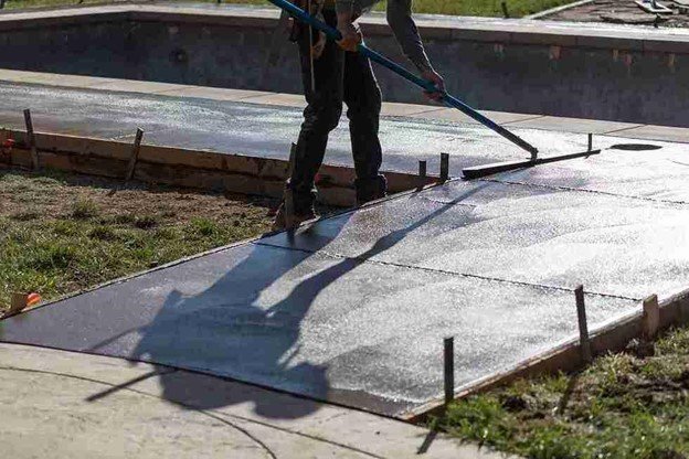 Concrete driveway installation with a worker smoothing freshly poured surface using a finishing tool in Eastlake, OH