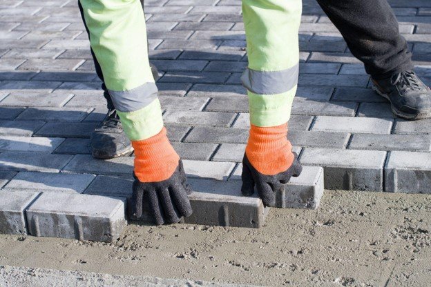 Concrete contractor placing brick pavers by hand for residential driveway installation in Eastlake, OH