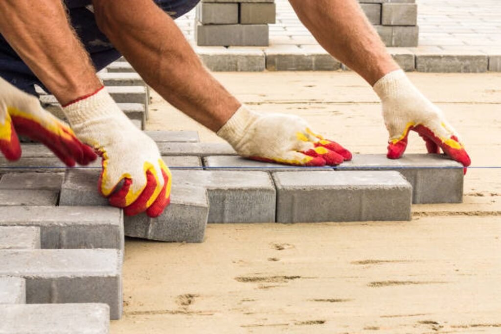 Contractor installing concrete pavers for patio construction on a leveled sand base in Eastlake, OH