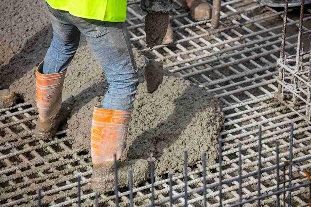 Worker pouring fresh concrete over steel rebar grid for structural slab construction in Eastlake, OH