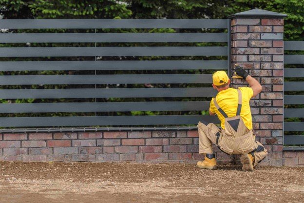 A worker working fence building with yellow hat on him.