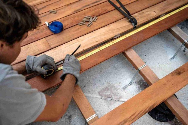 A worker working on deck installation holding while holding construction tape