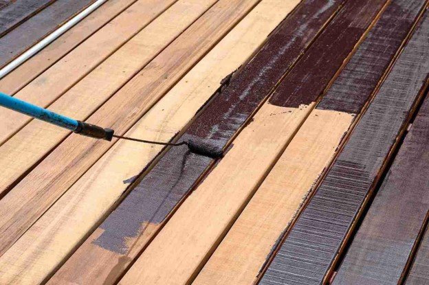 A paint roller painting deck with brown.