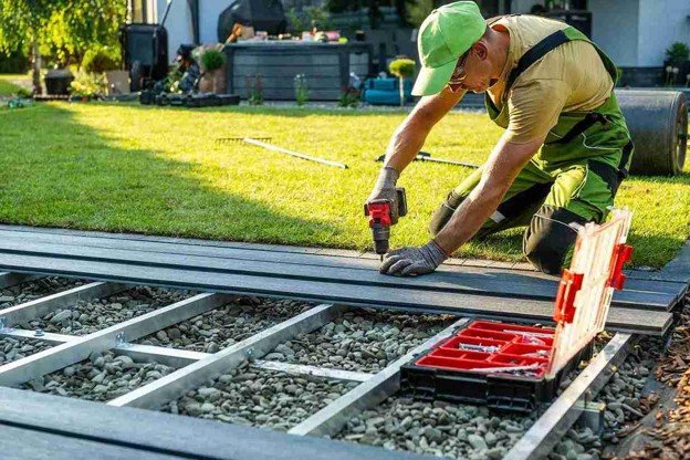 Worker drilling on wood with a box tool on side.
