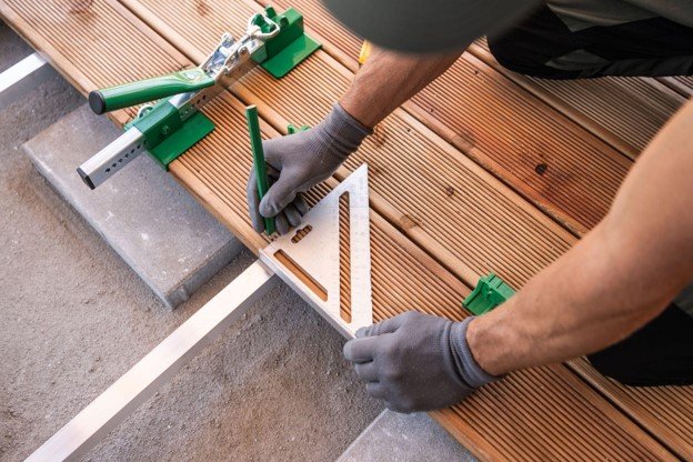Worker holding ruler while working on composite deck.