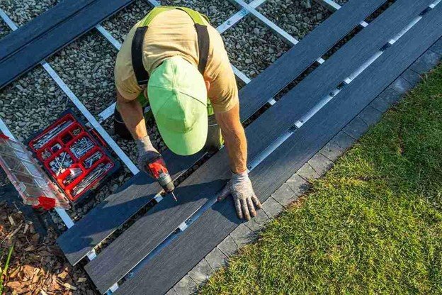 A man drilling on trex deck with tool holding.